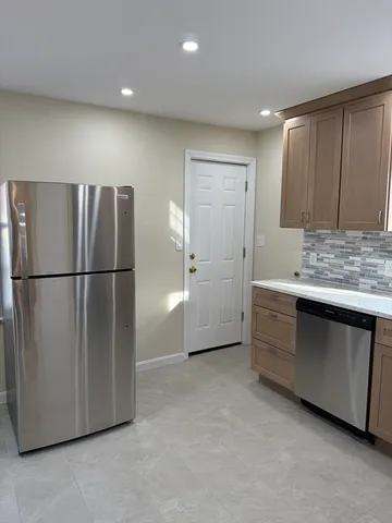 a view of kitchen with stainless steel appliances granite countertop refrigerator stove microwave and cabinets