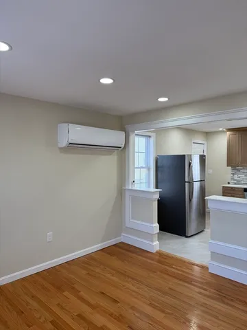 a view of a kitchen with refrigerator and wooden floor