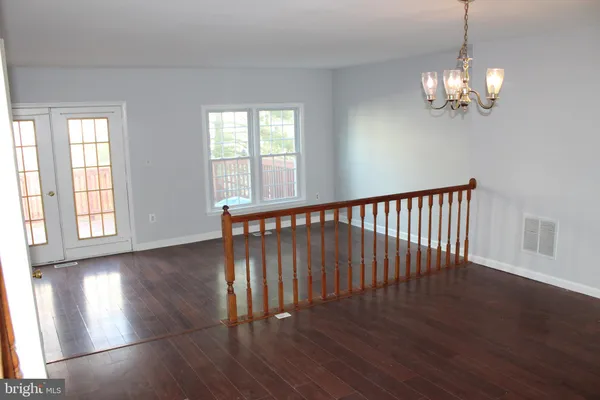 a view of a room with wooden floor chandelier and windows
