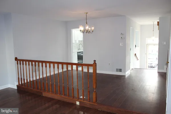 a view of a hallway with wooden floor and a chandelier