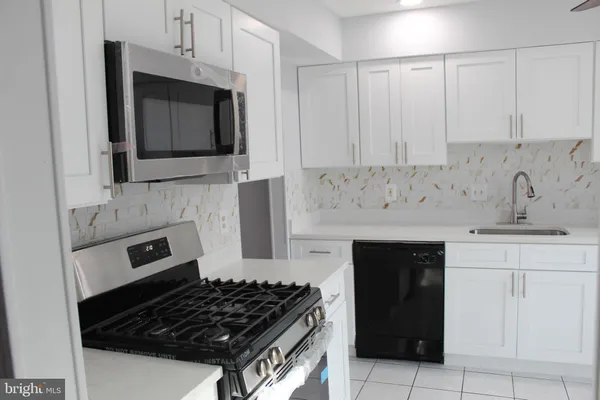 a kitchen with white cabinets and black appliances