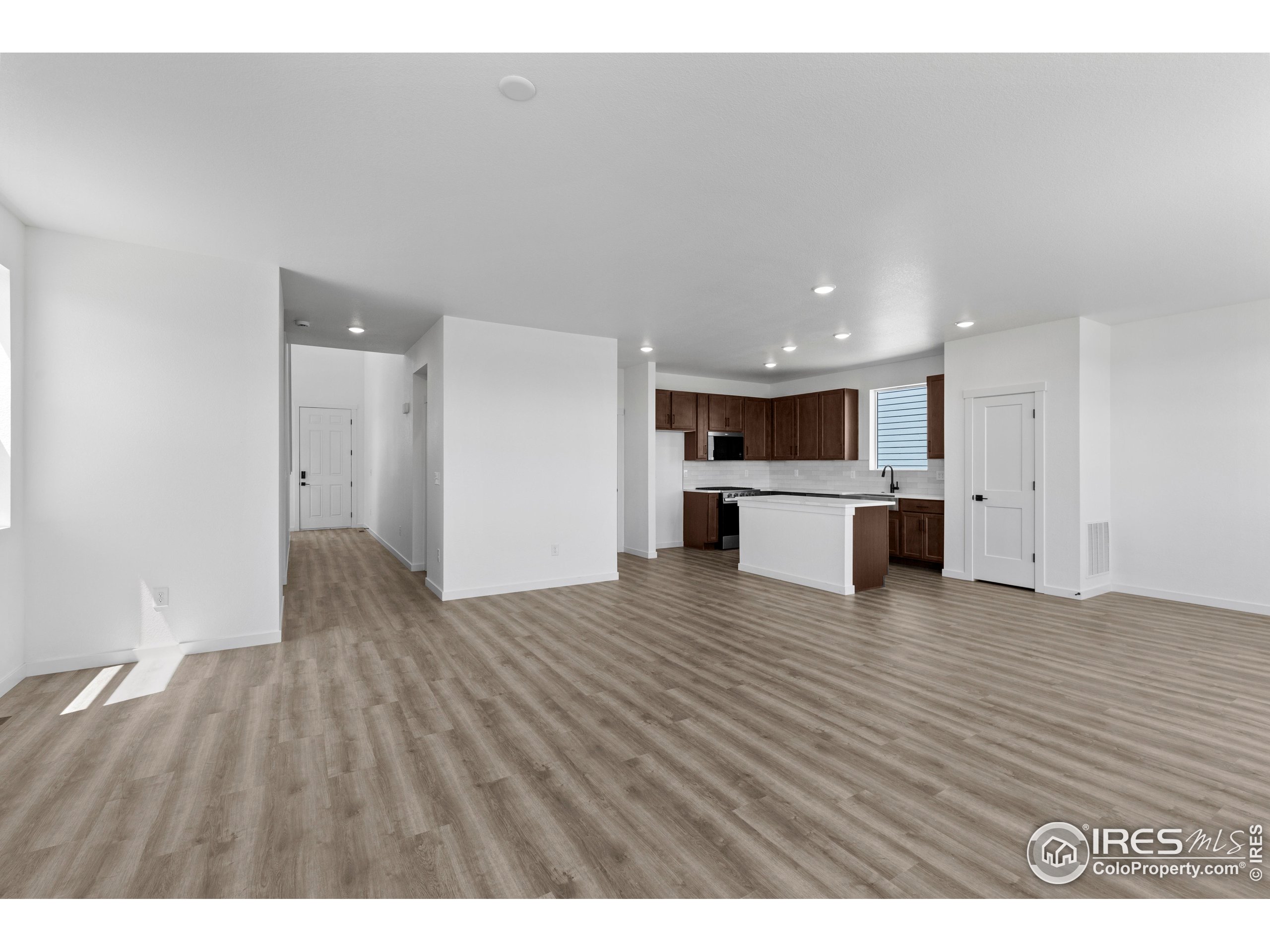737 Muturu Road Johnstown, CO 80534 - Photo 13 of 26 a view of kitchen and empty room with wooden floor