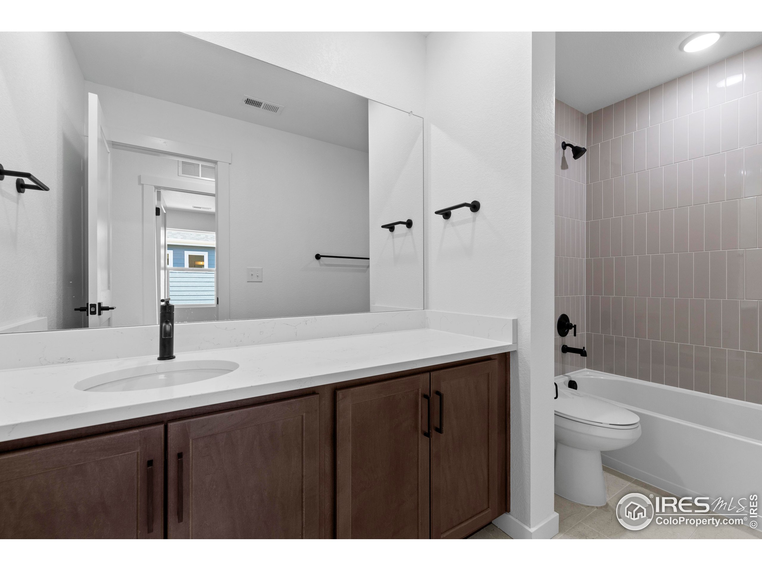 737 Muturu Road Johnstown, CO 80534 - Photo 22 of 26 a bathroom with a granite countertop sink toilet a large mirror a shower and a bathtub