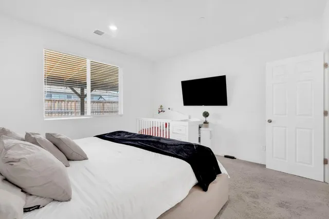 a bedroom with a bed and a flat tv screen on dresser