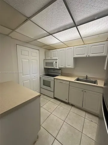 a kitchen with a sink a stove top oven and white cabinets