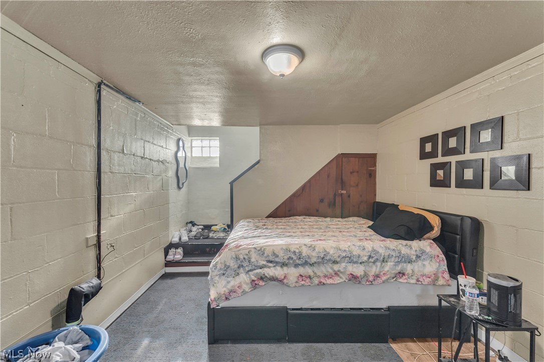 3962 Grosvenor Road South Euclid, OH 44118 - Photo 17 of 27 Lower-level room featuring painted cinder block walls, a durable gray floor covering, and a partial wood-paneled wall accent