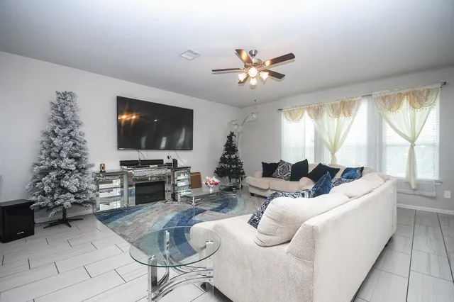 a living room with furniture a flat screen tv and a large window