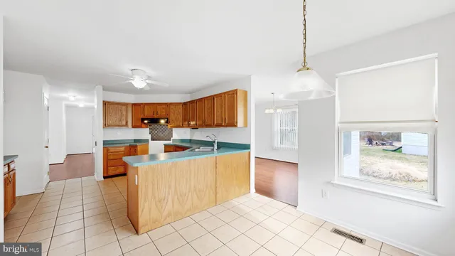 a view of a kitchen with kitchen island stainless steel appliances wooden floor and a chandelier