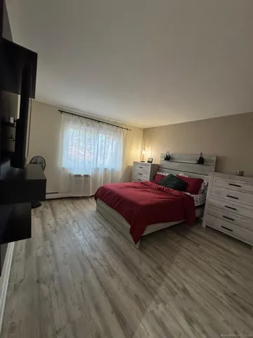 a spacious bedroom with a bed and wooden floor