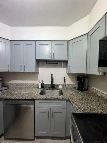 a kitchen with granite countertop a sink a stove and cabinets