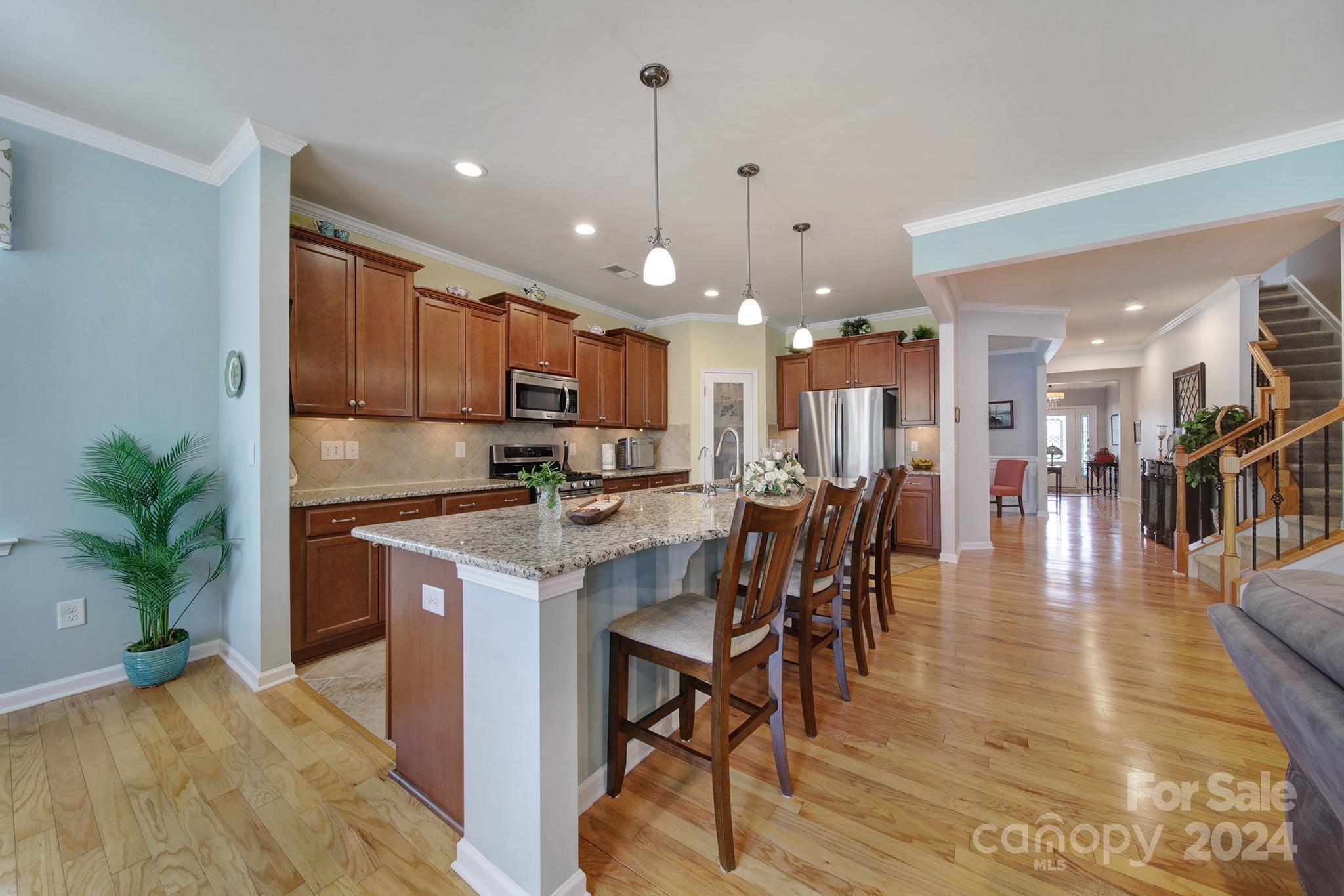 4362 Perth Road Fort Mill, SC 29707 - Photo 6 of 34 a kitchen with stainless steel appliances kitchen island granite countertop a stove a refrigerator a kitchen island a dining table and chairs with wooden floor