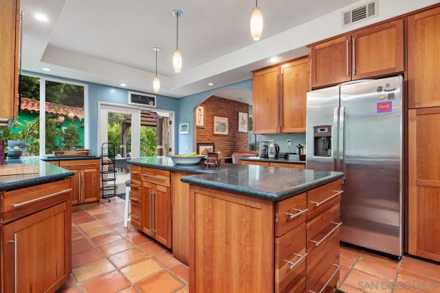 a kitchen with stainless steel appliances granite countertop a refrigerator a sink dishwasher a stove and a dining table with wooden floor