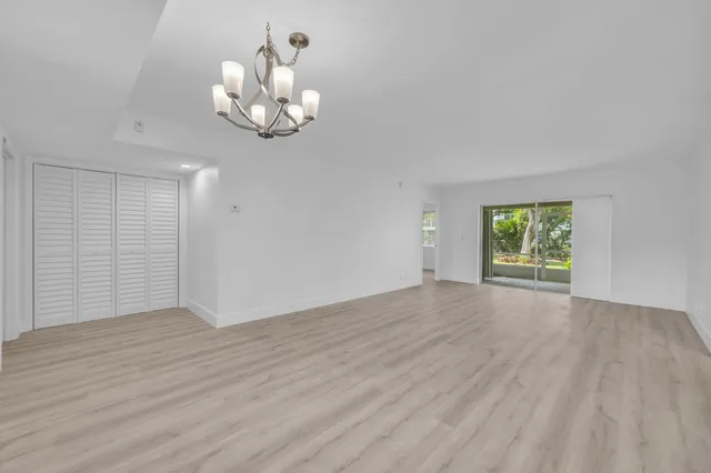 an empty room with wooden floor cabinet and windows