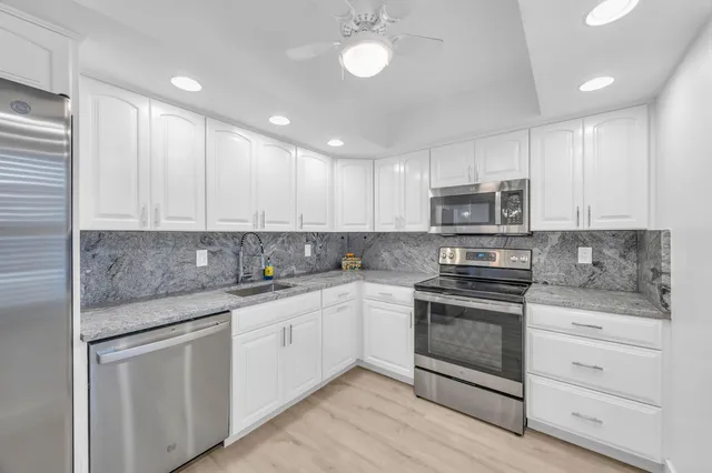 a kitchen with stainless steel appliances granite countertop a sink and cabinets
