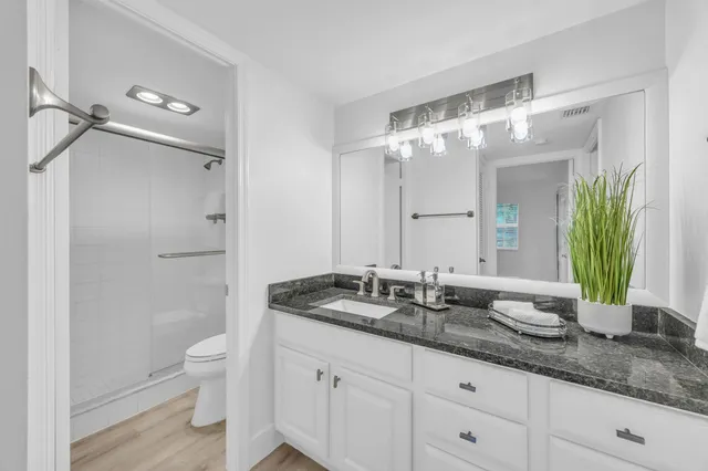 a bathroom with a granite countertop sink a toilet and a mirror