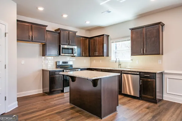 a kitchen with stainless steel appliances granite countertop a stove top oven a sink and dishwasher a refrigerator with wooden floor