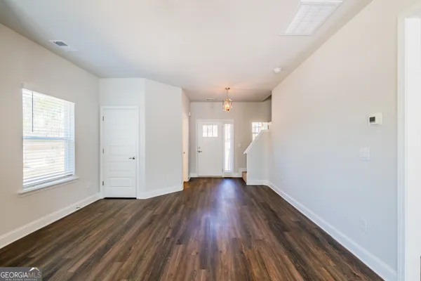 a view of an empty room with wooden floor and windows