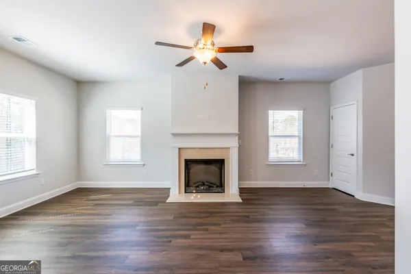 a view of an empty room with wooden floor fireplace and a window
