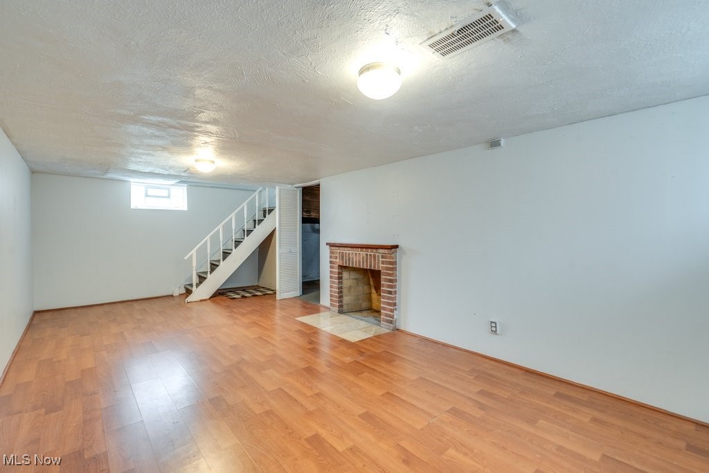 13677 Cedar Road Cleveland, OH 44118 - Photo 45 of 50 Below grade area featuring a fireplace, a textured ceiling, light wood-type flooring, and stairs