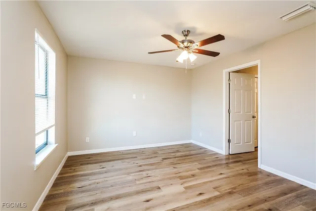 a view of empty room with wooden floor and fan