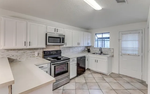 a kitchen with white cabinets appliances and sink