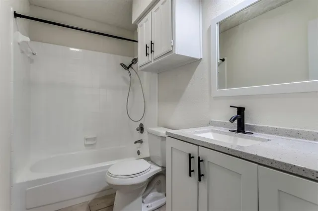 a bathroom with a granite countertop sink a toilet and shower