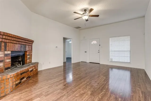 an empty room with windows a fireplace and wooden floor