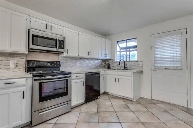 a kitchen with granite countertop white cabinets stainless steel appliances and a window
