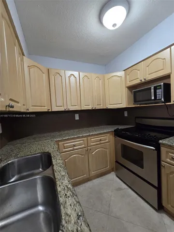 a kitchen with granite countertop a stove sink and cabinets
