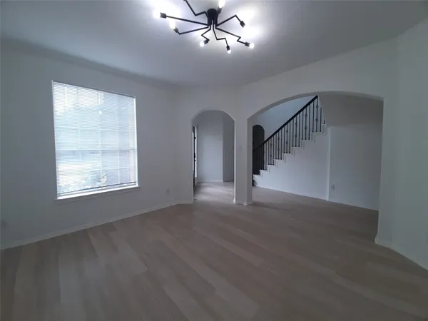 a view of an empty room with wooden floor ceiling fan and windows