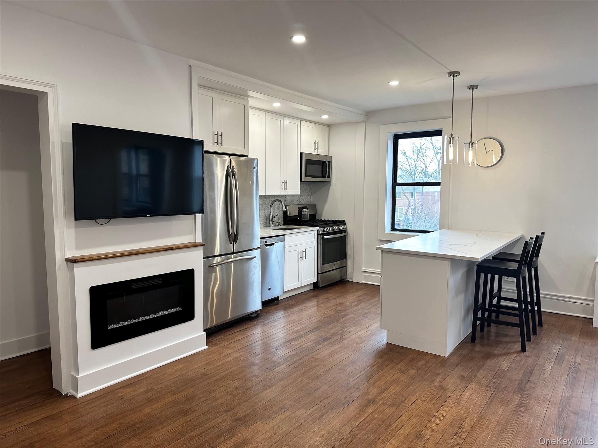 4810 Boston Post Road, Unit 4E Pelham, NY 10803 - Photo 4 of 26 a kitchen with stainless steel appliances a stove a microwave and white cabinets
