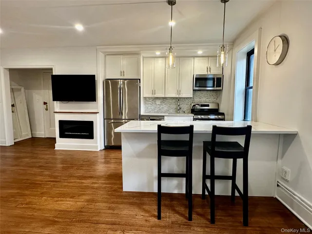 a kitchen with granite countertop a stove a microwave a dining table and chairs with wooden floor