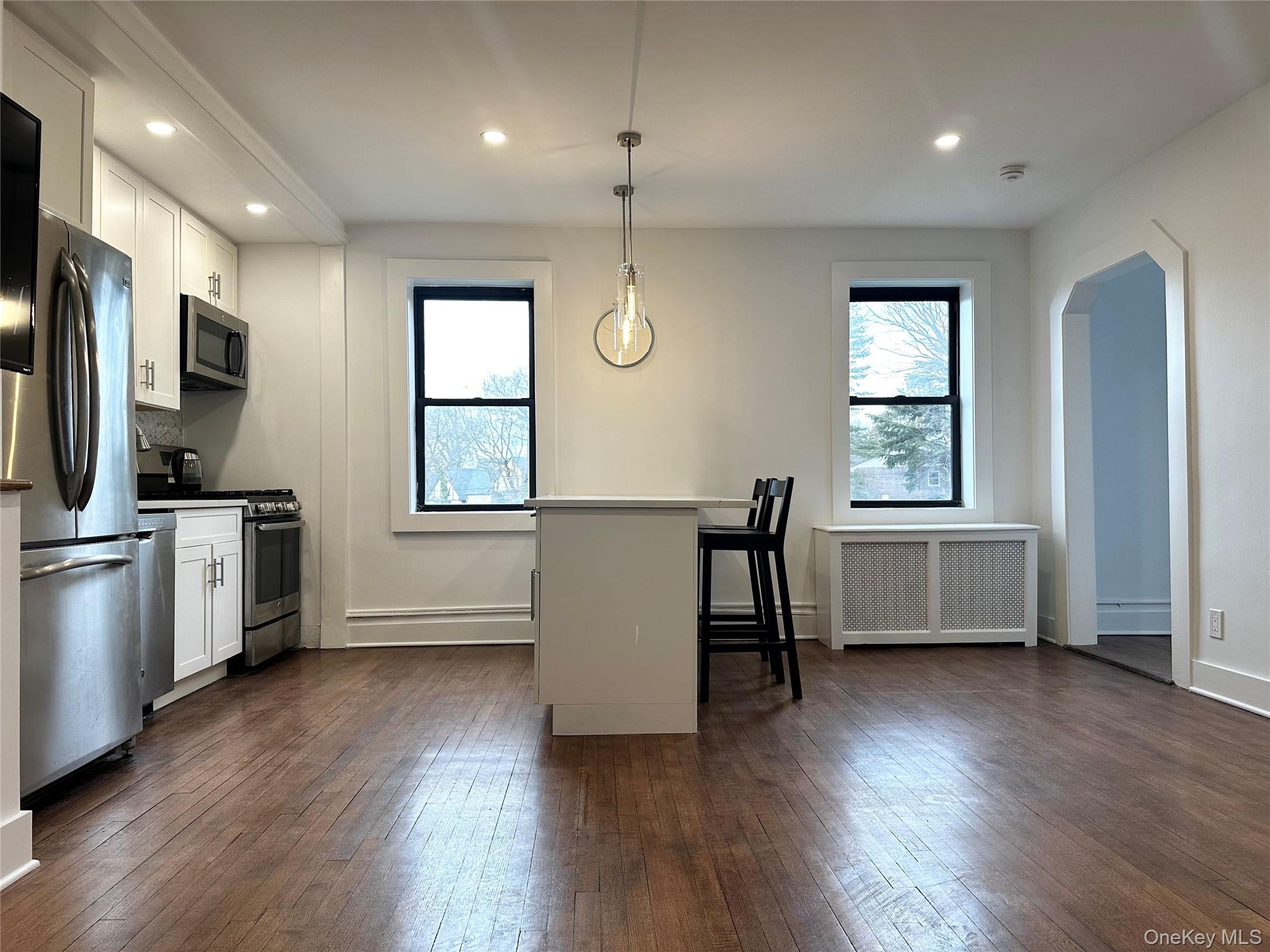 4810 Boston Post Road, Unit 4E Pelham, NY 10803 - Photo 6 of 26 a kitchen with stainless steel appliances granite countertop a refrigerator a sink dishwasher a stove and white countertops with wooden floor