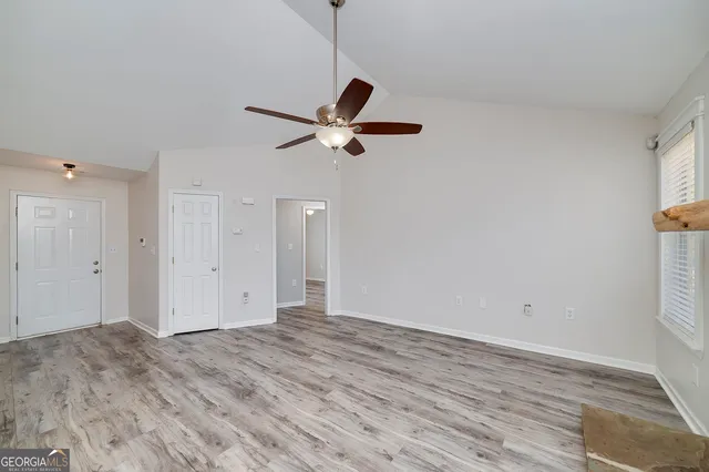 a view of empty room with wooden floor and fan
