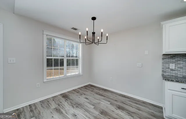 an empty room with wooden floor fireplace and windows