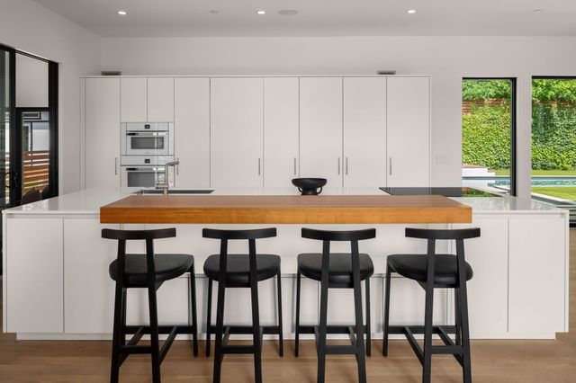 a kitchen with stainless steel appliances granite countertop a stove top oven a sink a dining table and chairs with wooden floor