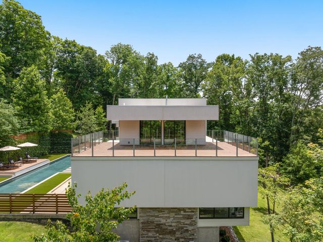 a view of swimming pool with seating space and trees in the background