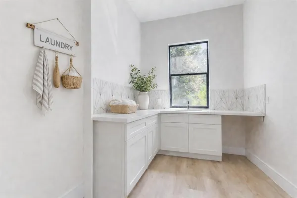 a kitchen with white cabinets and window