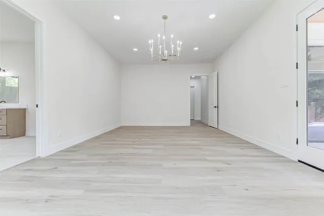 a view of an empty room with chandelier and fire place