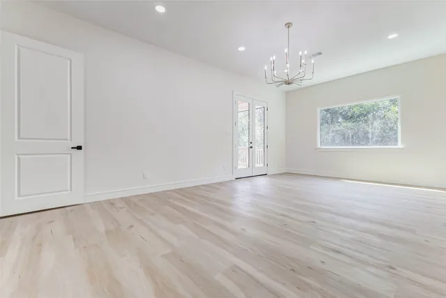 a view of an empty room with wooden floor and a chandelier