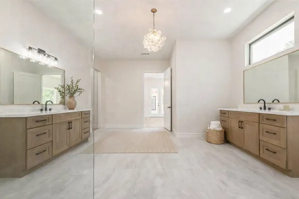 a spacious bathroom with double vanity sink a two mirror a window and a bathtub