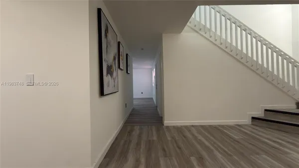 a view of a hallway with wooden floor and stairs