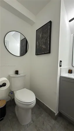 a white toilet sitting next to a bathroom sink and a mirror