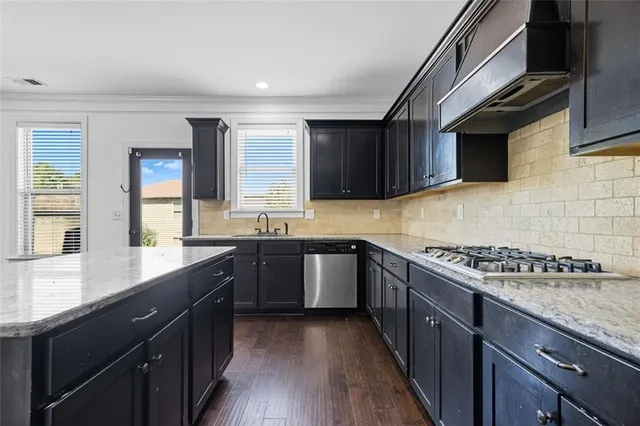a kitchen with stainless steel appliances granite countertop wooden cabinets a stove top oven a sink and dishwasher