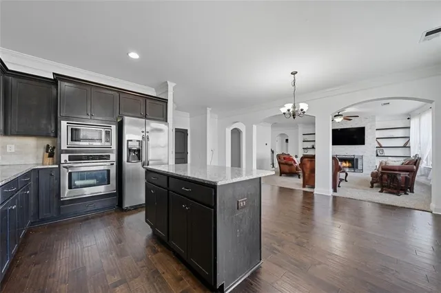 a kitchen with stainless steel appliances kitchen island granite countertop a refrigerator a stove oven and a sink with cabinets