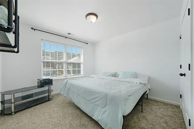 a bed sitting in a spacious bedroom next to a window