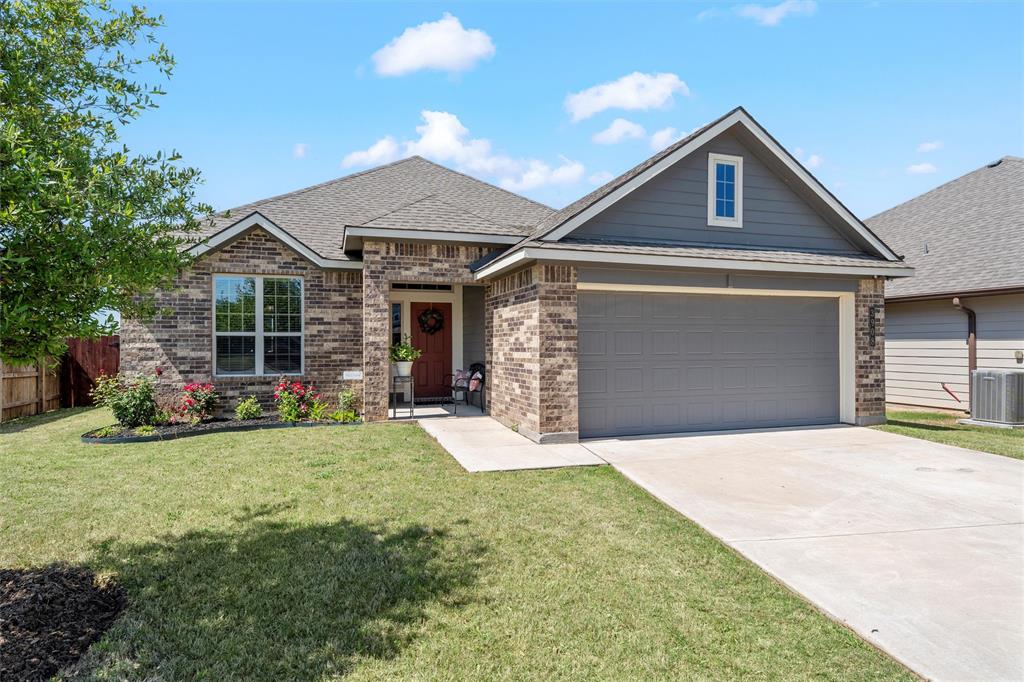 View of front of home featuring brick siding, a front lawn, fence, and driveway