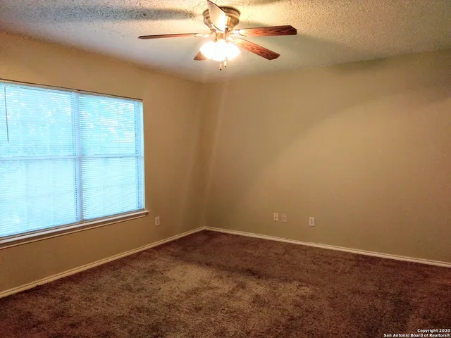 an empty room with a window and a ceiling fan