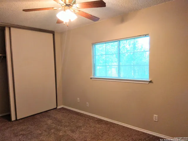 an empty room with a window and a fan