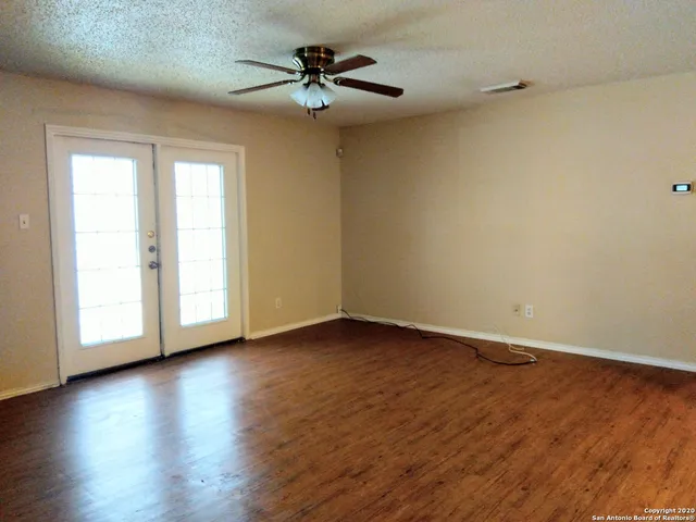 a view of an empty room with wooden floor and a window